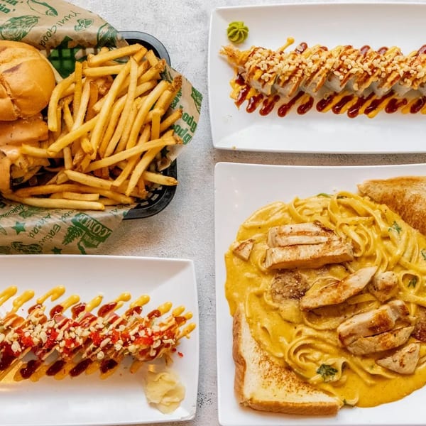 Top-down view of a burger and fries, two sushi rolls, and chicken pasta with toast.