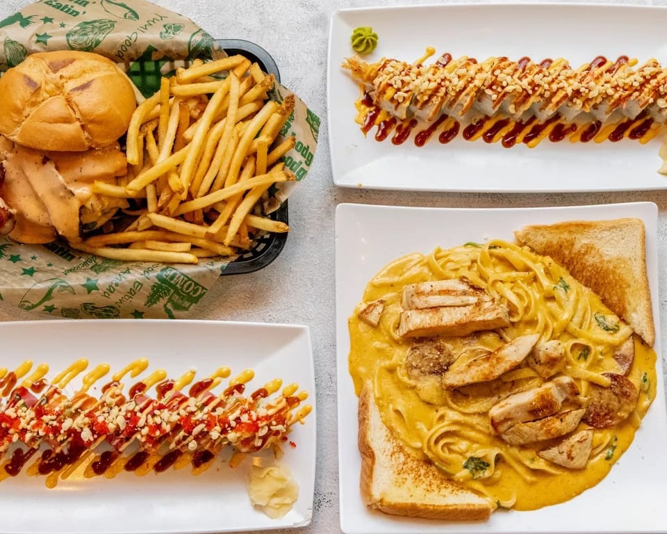 Top-down view of a burger and fries, two sushi rolls, and chicken pasta with toast.